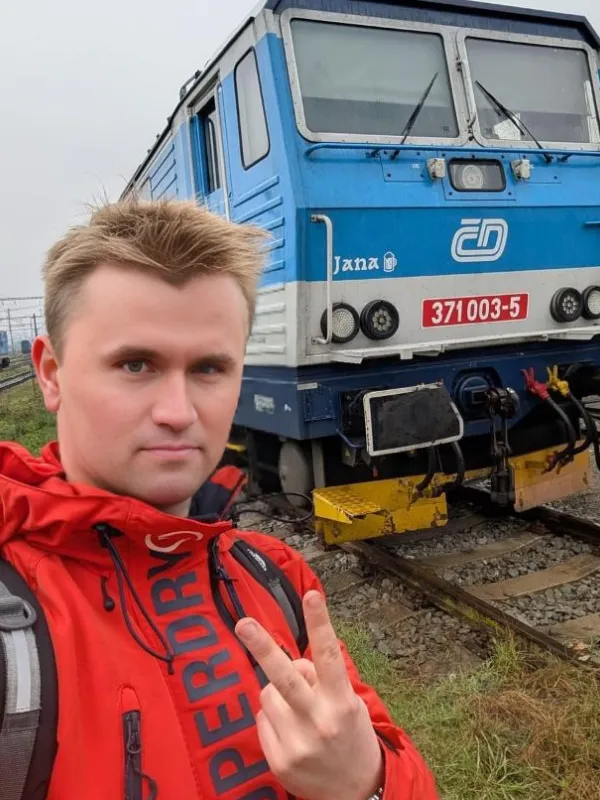 Charlie Kirk tiny face meme in front of blue locomotive by Kirkify AI